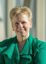 Professional headshot of Dorri Raposa, wearing a green jacket in front of a light colored background.