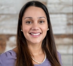 Professional headshot of Victoria Palek, wearing a lavender shirt in front of a light stone background.