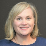 Woman smiling with should length blonde hair in a blue blouse