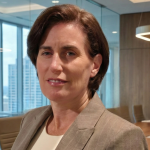 Woman with short brown hair wearing a gray blazer and white blouse