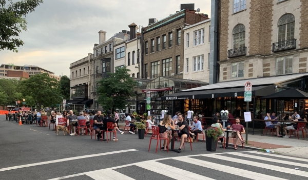 People eating at tables in the street.