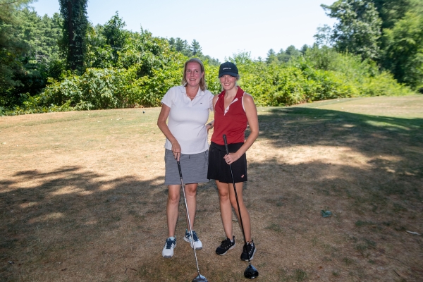 Two people holding golf clubs pose for a photo (WTS Boston).