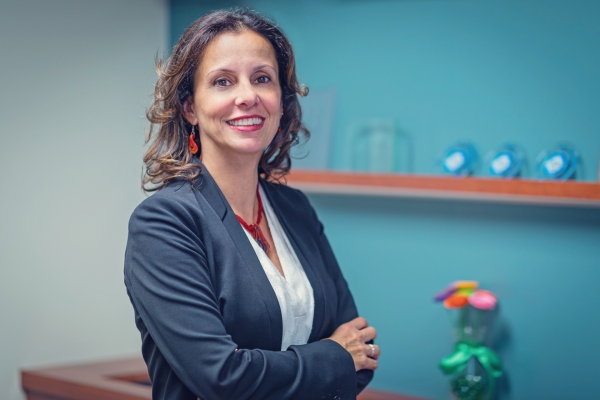 Luciana Burdi wearing navy blue blazer and white shirt in an indoor setting.