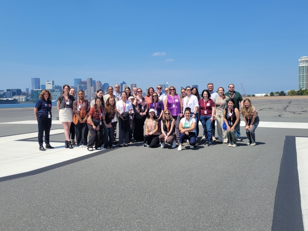  WTS-Boston Summer Tour attendees on a Boston Logan International Airport airfield runway with the downtown Boston skyline in the background. 