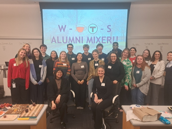 a photo of a group of young adults posing in a group in front of a screen that reads 'WTS Alumni Mixer'.