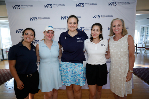 A group of five women smiling in front of WTS backdrop