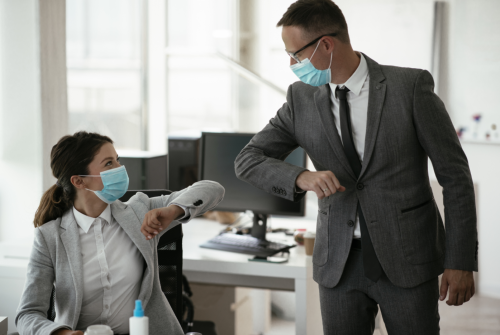 Two people in masks touching elbows