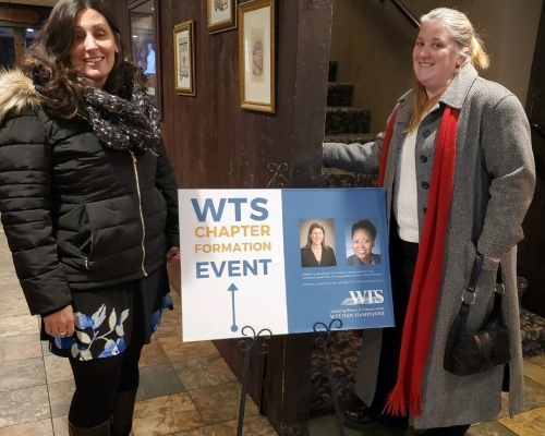 Two attendees with event sign