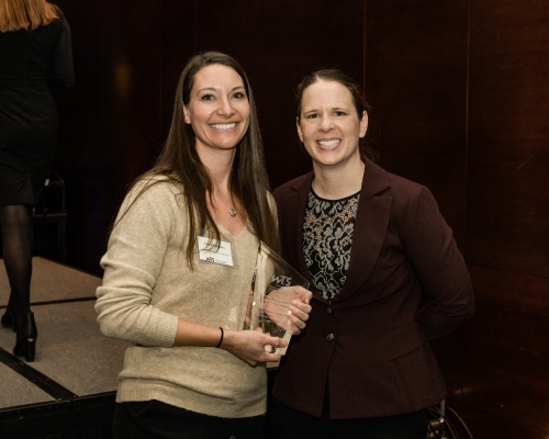 Woman holding award next to other woman