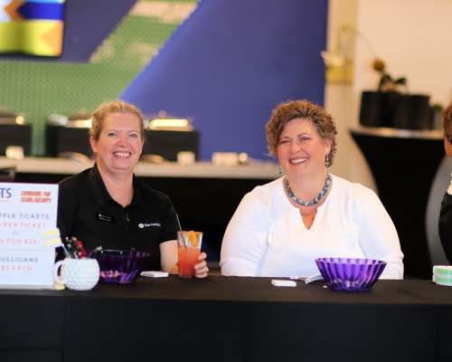 Two women sit behind a check-in table