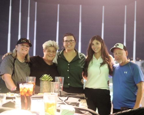 Group of people sit around a table at Topgolf