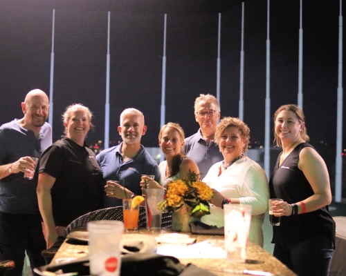 Group of people sit around a table at Topgolf