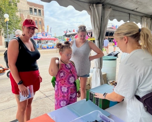 Photo of a family visiting the WTS booth on STEM day at Iowa State Fair 2023