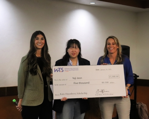 3 women stand with a giant check in front