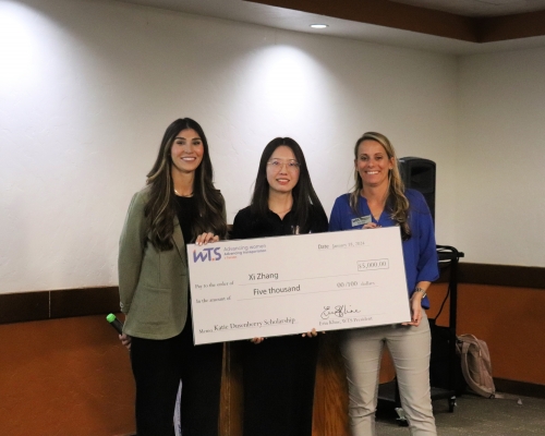 3 women stand with a giant check in front