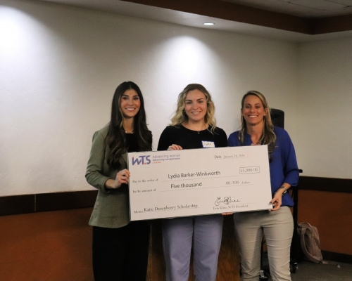 3 women stand with a giant check in front