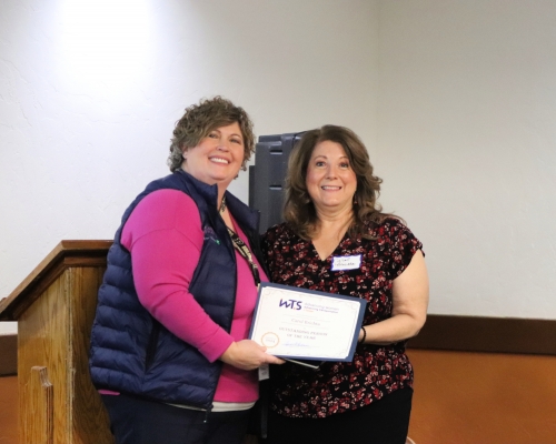 2 women are facing the camera holding an award