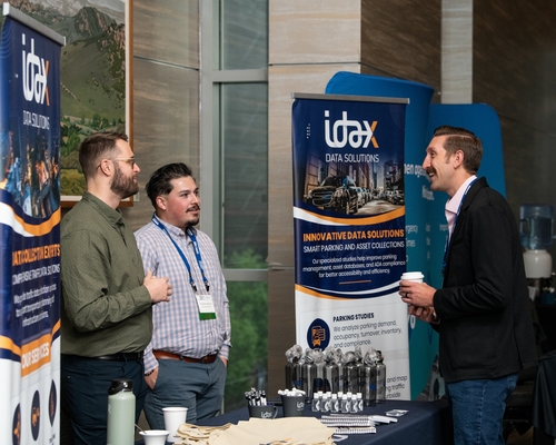 A person talking to two people at the innovative data solutions table. 