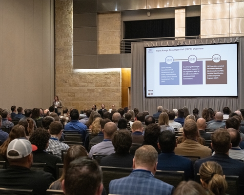 A large group of people listening to a presentation in a conference room. 