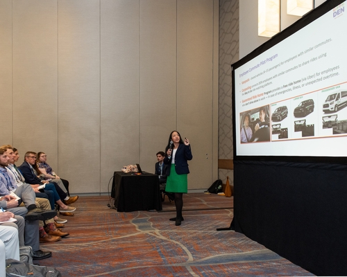 A presenter at the Transportation Symposium speaking to a large group of people. 