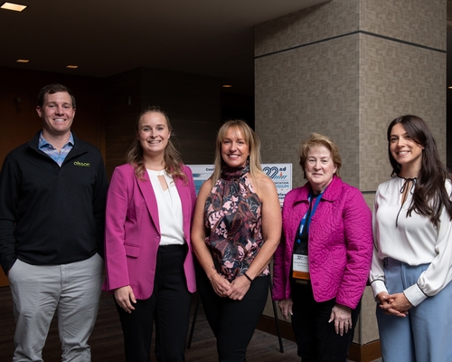 A group of five people smiling at the Denver Transportation Symposium. 