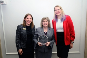 WTS-Boston President Gina Solman and Vice President Sarah Bergman posing with award winner Stephanie Pollack and her glass award