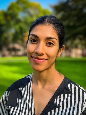 Headshot of Aanchal Chopra wearing a black and white striped shirt in an outdoor setting.