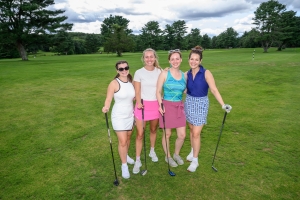 A third foursome of women golfers posing on a golf course.