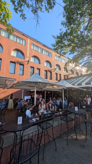 Outdoor patio of a restaurant with people socializing under umbrellas.