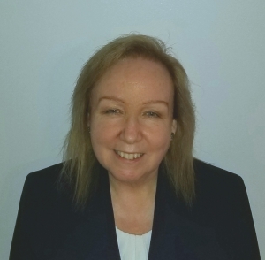 Headshot of a blonde woman in a dark suit jacket looking straight at the camera.
