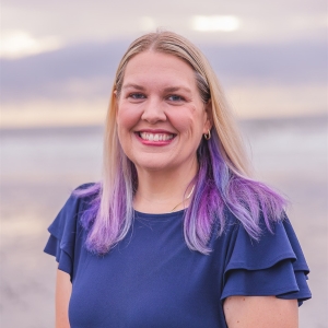Woman smiling wearing a blue blouse with blonde and purple hair