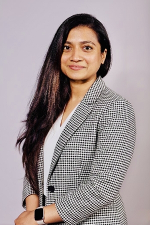 Woman with long brown hair in a gray checkered blazer